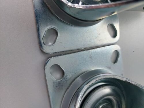 Castor top plate showing burrs around mounting holes